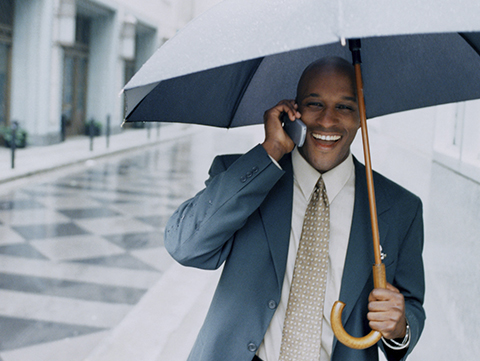 Man talking on cellphone holding open umbrella