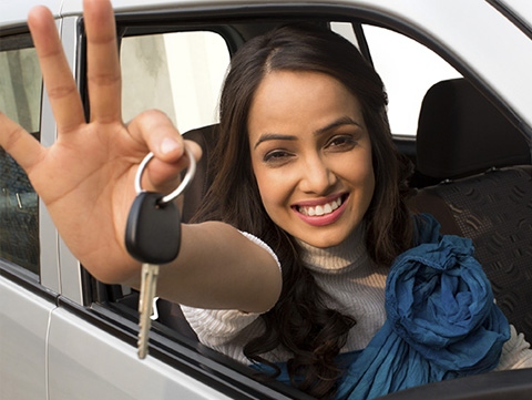 Woman sitting in car holding key out window