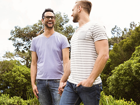 Two men holding hands and smiling at each other