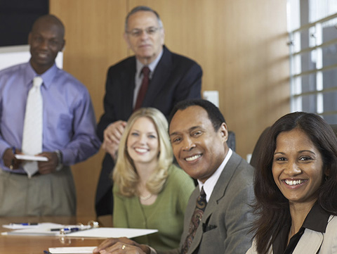 Group of businessmen and women sitting around a conference table