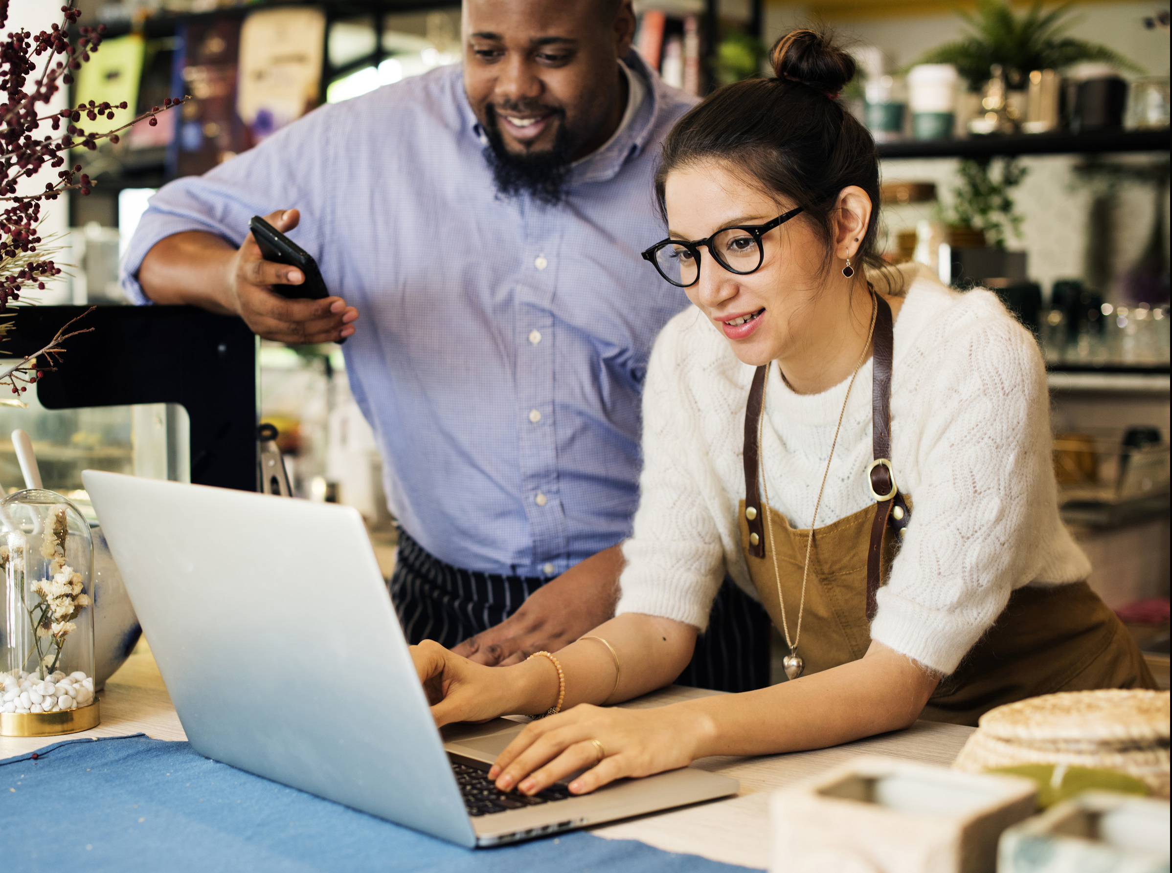 Shop keeper and customer looking at laptop