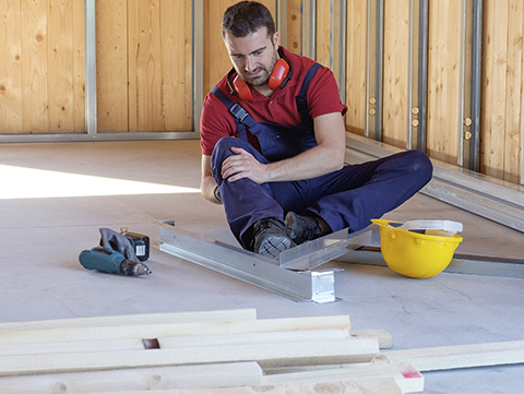 Construction worker sitting on job site holding his leg