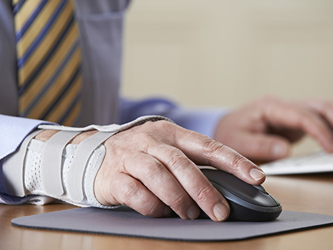 Close up of businessman with arm in a brace working at computer