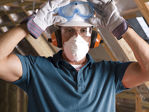 Worker in protective gear including gloves, mask and googles