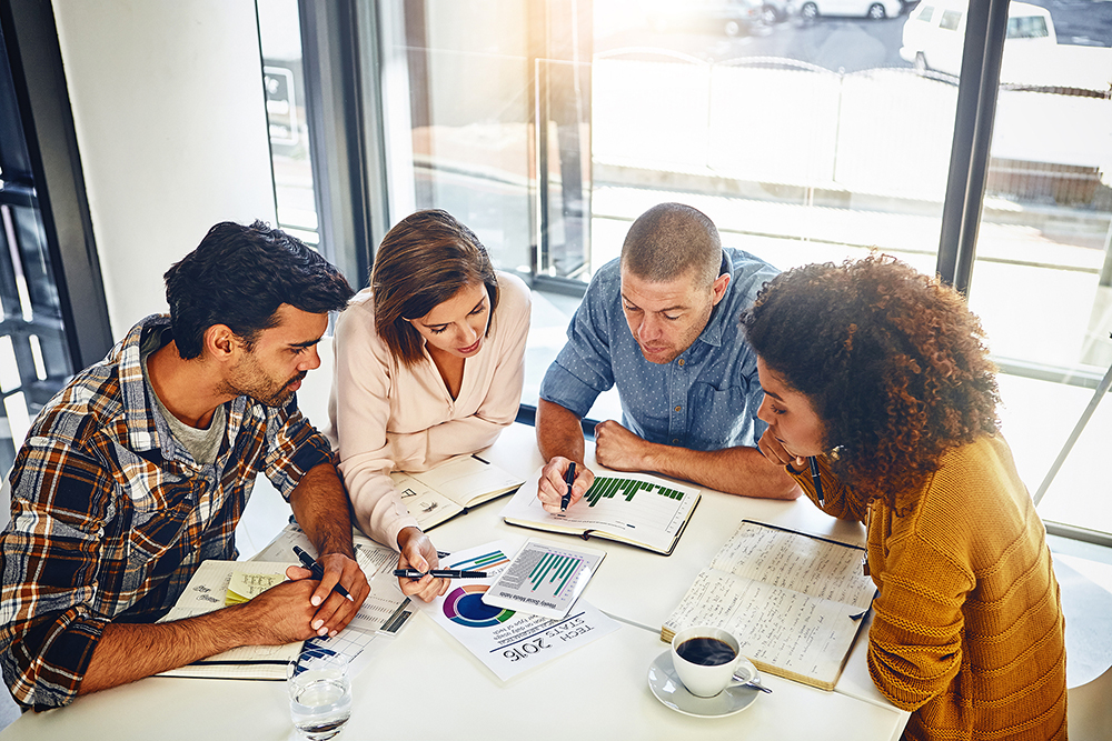 Group of workers sitting at table reviewing documents