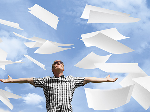 Man stretching his arms with pieces of paper falling from the sky